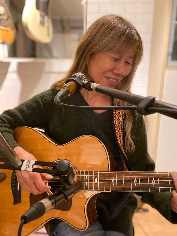 Portretfoto van Sioe Tio met een gitaar in haar handen